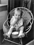 361079 Afbeelding van een kind in een rotan stoeltje.